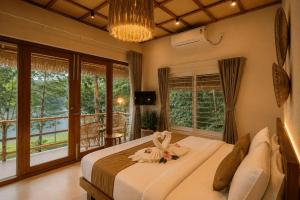 a bedroom with a large bed and a balcony at Ayana Lake Resorts in Kovillūr