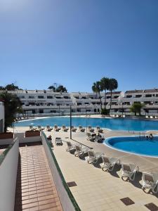 a large swimming pool with lounge chairs and a building at Marys Place in Costa Del Silencio