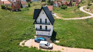a white house with a car parked in front of it at Vila Paola in Kupres