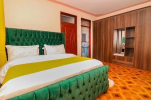 a bedroom with a large bed with a green headboard at Toquee Hotel Bookings - Nairobi in Nairobi