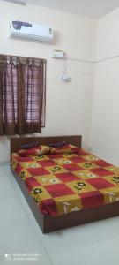 a bed with a quilt on it in a room at Velli apartment in Tirunelveli