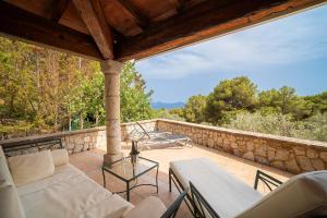 a patio with white furniture and a stone wall at Can Xilla by Sealand Villas in Alcudia