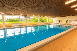 a large swimming pool with blue water in a building at Apartment Rehberg 14 OG Panorama Balkon Pool Sauna in Braunlage
