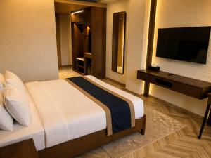 a hotel room with a bed and a flat screen tv at Basilica Resort, Lonavala in Lonavala