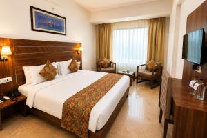 a hotel room with a bed and a flat screen tv at Amritara Ramila Kutir Ayodhya in Ayodhya
