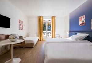 a hotel room with two beds and a tv at B&B HOME Brides-les-Bains Les 3 Vallées in Brides-les-Bains +53 photos