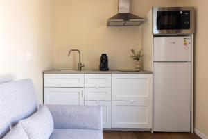 a kitchen with white cabinets and a white refrigerator at La Casa Contenedor Loft in Zaragoza +15 photos