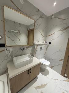 a bathroom with a sink and a mirror and a toilet at The Chinmaye Grand in Bhāgalpur