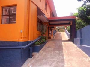 an orange building with a sidewalk next to a building at Honey Palace Homestay in Madikeri