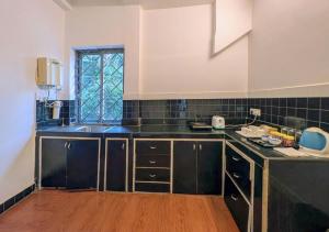 a kitchen with black cabinets and a window at Beach villa Candolim in Candolim