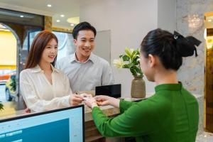 a man and woman standing at a table with a child at Nature Hotel Da Lat - Le Dai Hanh in Da Lat