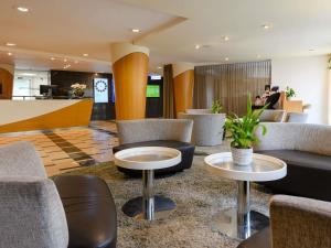 a lobby with couches and tables in a hotel at Mövenpick Hotel Egerkingen in Egerkingen