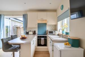 a kitchen with white cabinets and a table with fruit on it at Ashclose Lodge Annexe in Sherborne