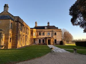 an old brick building with a grass yard at Ashclose Lodge Annexe in Sherborne
