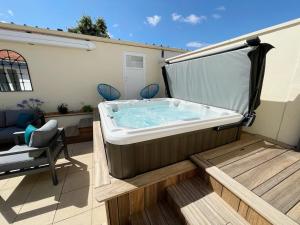 a hot tub sitting on a deck with a chair at Le Rivage, maison proche mer avec Spa in Les Sables-d'Olonne