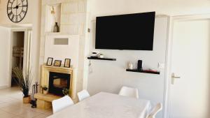a dining room with a table and a television on the wall at Le Rivage, maison proche mer avec Spa in Les Sables-d'Olonne