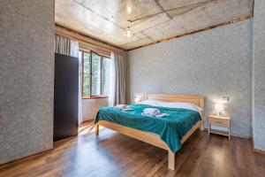 a bedroom with a bed with a green blanket at Muros Guesthouse in Mestia