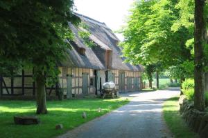 un vecchio fienile con un tetto di paglia e una strada di Ferienhaus nahe Ostsee mit Sauna, Kamin & eingezäuntem Garten,Hund willkommen a Rabenholz