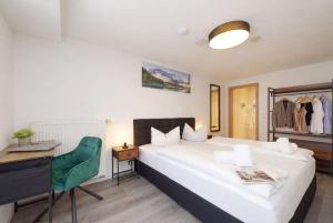 a bedroom with a bed and a desk and a green chair at Hotel Bayerisch Meran in Bad Feilnbach