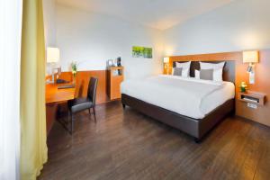 ein Hotelzimmer mit einem Bett und einem Schreibtisch und einem Bett und einem Schreibtisch in der Unterkunft Best Western Premier IB Hotel Friedberger Warte in Frankfurt am Main