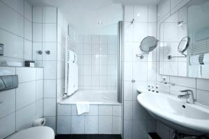 ein weißes Badezimmer mit Badewanne und Waschbecken in der Unterkunft Best Western Premier IB Hotel Friedberger Warte in Frankfurt am Main + 85 Fotos