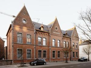 a large brick building with two cars parked in front of it at Apartment for 4 guests in Bree in Bree