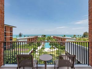 a balcony with chairs and a table and the ocean at Pullman Khao Lak Resort in Khao Lak +268 photos