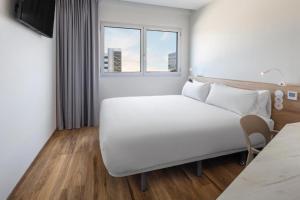 a white bed in a hotel room with a window at B&B HOTEL Lisboa Aeroporto in Lisbon +29 photos