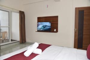 a bedroom with a bed with a tv on the wall at D D Luxury Inn in Chikmagalūr