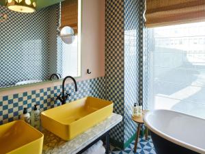 a bathroom with a yellow sink and a tub at 25hours Hotel Indre By in Copenhagen +75 photos