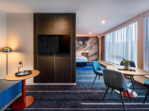 a hotel room with two tables and a bed at Novotel Melbourne Preston in Melbourne