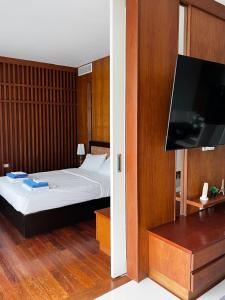 a bedroom with a bed and a flat screen tv at Q Kata Residence in Kata Beach