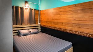 ein kleines Bett in einem Zimmer mit einer Holzwand in der Unterkunft โรงแรมคุ้มเดช - KoomDech Hotel in Sattahip