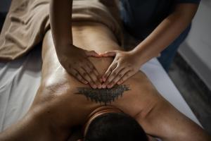 a man getting a tattoo on his back at The Beach Wellness Residence in Ban Pru Yai