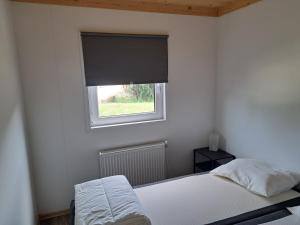 a white bedroom with a bed and a window at Cube 97 I 4 persoons chalet met hottub in Zennewijnen