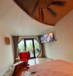a person holding a glass of wine in a bedroom at Hobbitul lui Maș in Valea lui Maş