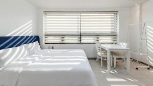 a bedroom with a bed and a table and a window at Yeosu Onueli Pension in Yeosu