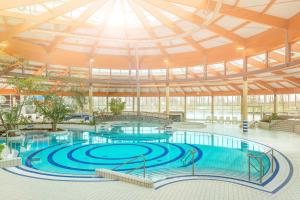 a large pool with blue water in a building at Ferienhaus "Stella Olivia" - Bade- & Saunawelt täglich inklusive in Lobbe