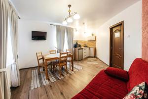 a living room with a table and a red couch at Pension La Roata in Gura Humorului