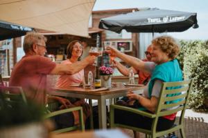 Eine Gruppe von Menschen sitzt an einem Tisch und trinkt Wein in der Unterkunft De Pastorie in Borgloon