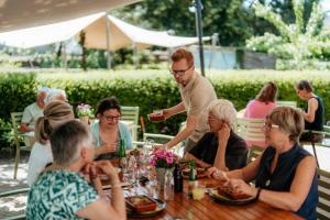 Eine Gruppe von Menschen sitzt um einen Tisch in der Unterkunft De Pastorie in Borgloon