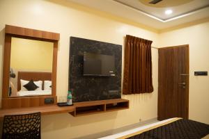 a room with a tv and a bed and a mirror at RMA Joliday Inn in Pondicherry