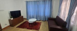 a living room with a couch and a table and a television at Aangan Homestay in Pātan