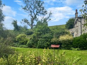 an old stone house with a bench in the yard at Granary Cottage in Kirkby Malham