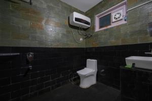 a bathroom with a toilet and a tv on the wall at Splendid Retreat Hotels Kufri in Kūfrī