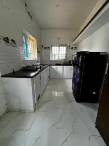 a large white kitchen with a black refrigerator in it at Villa Stay in Pondicherry