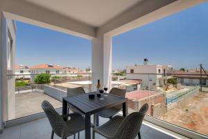 a dining room with a table and chairs and large windows at Oasis Luxury Escape in Xylophaghou