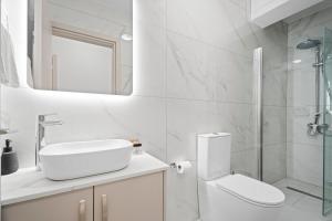 a white bathroom with a toilet and a shower at Oasis Luxury Escape in Xylophaghou +12 photos