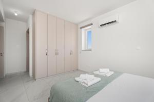 a white room with a bed and white cabinets at Oasis Luxury Escape in Xylophaghou