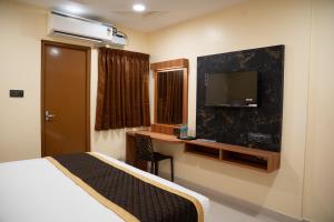 a hotel room with a bed and a desk and a tv at RMA Joliday Inn in Pondicherry